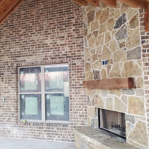 Outdoor stone fireplace with cedar mantel by Mendoza Masonry